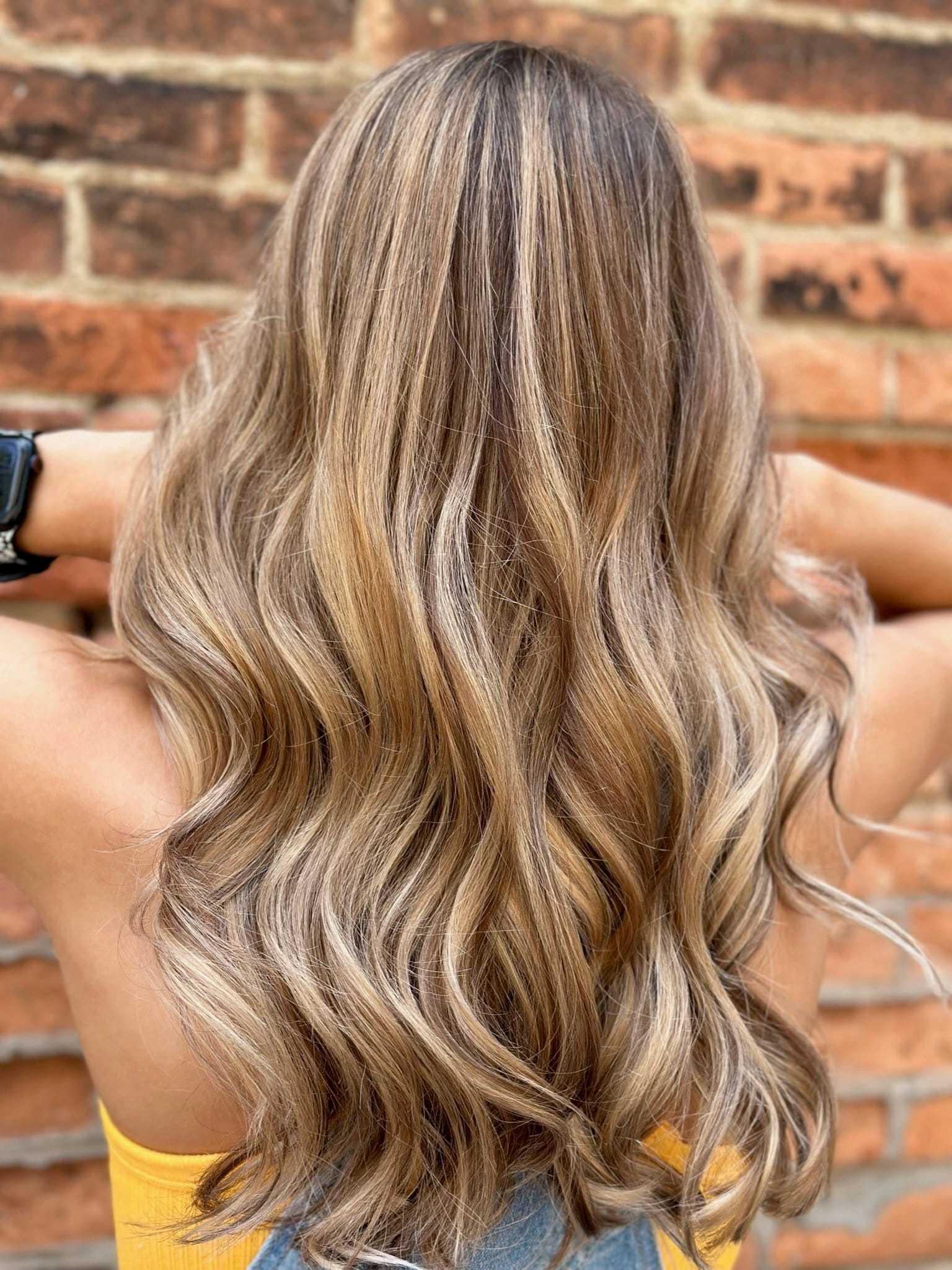 Wavy blonde hair in front of a brick wall.