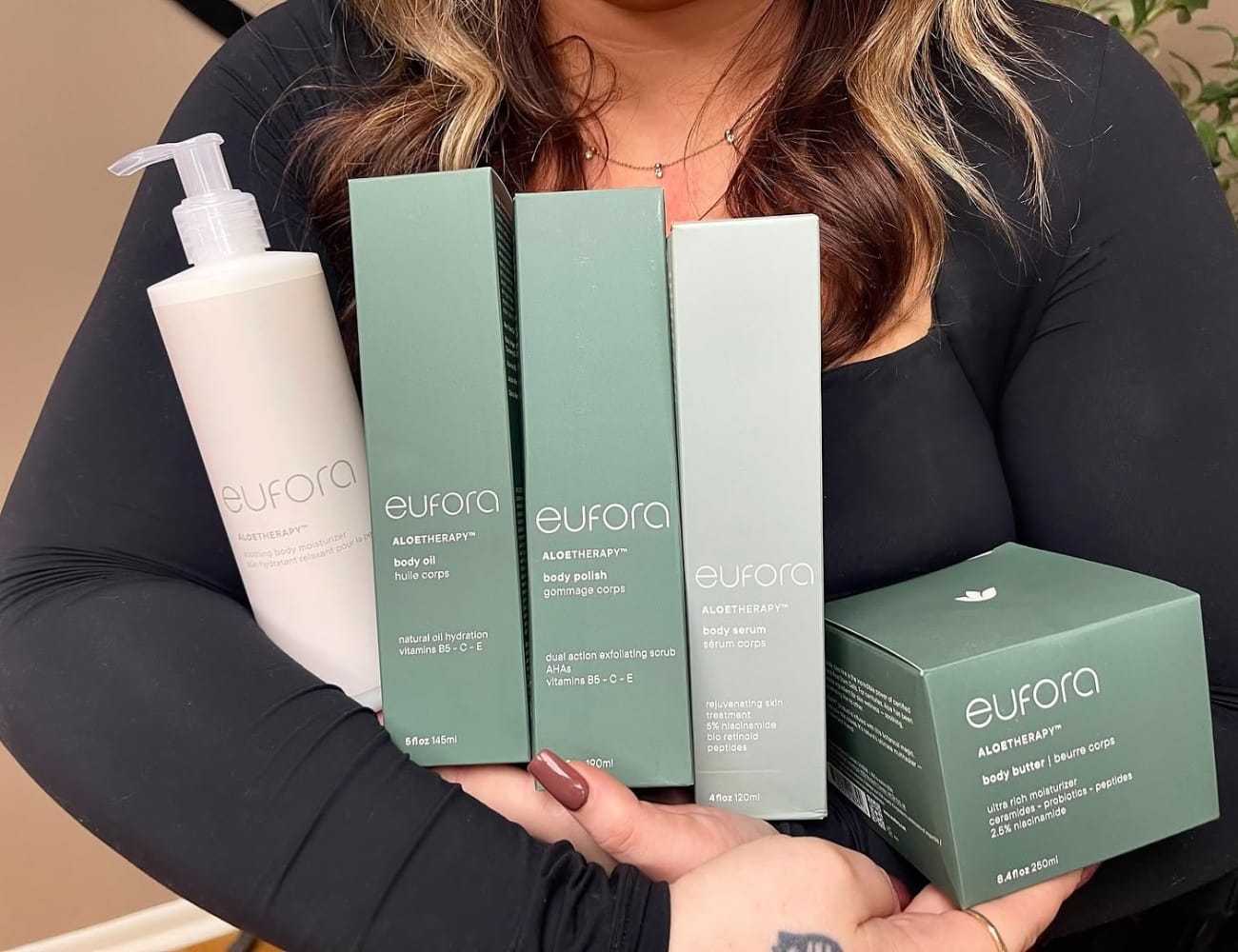Person holding Eufora body care products including bottles and boxes.