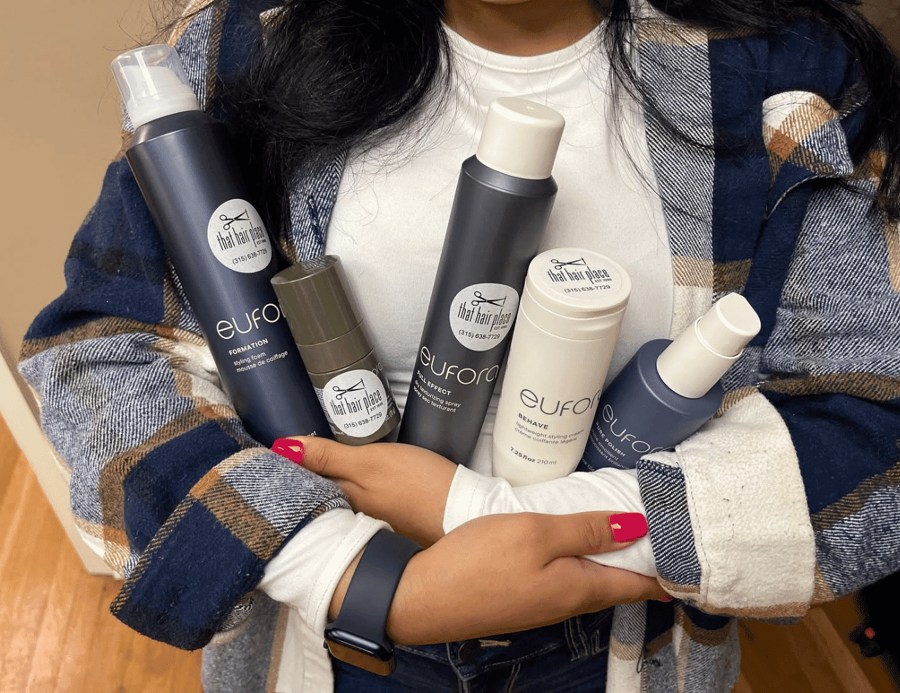 A person holding a variety of Eufora hair care products in their arms.