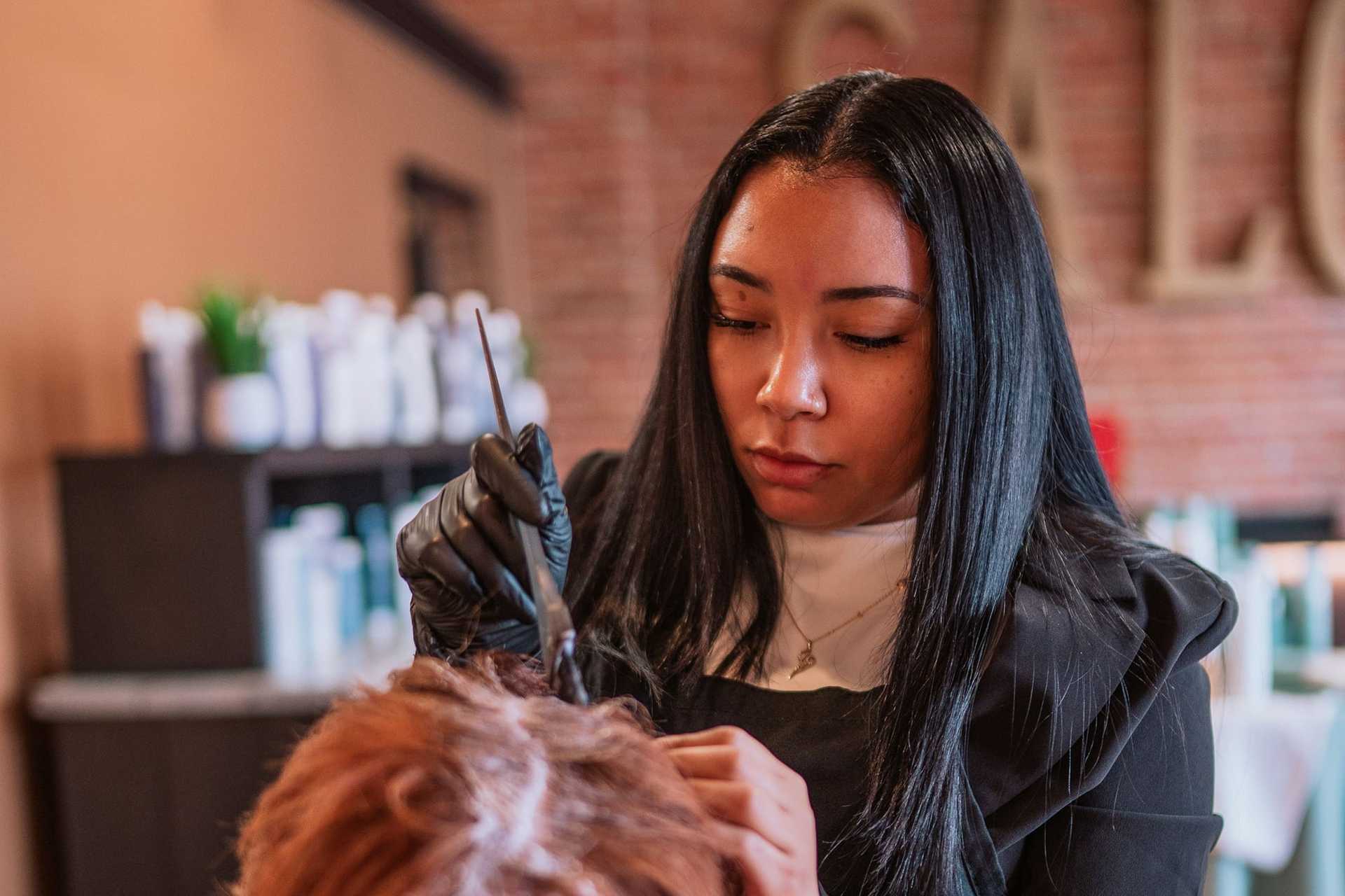 Hairdresser focused on dyeing a client's hair in a salon setting.